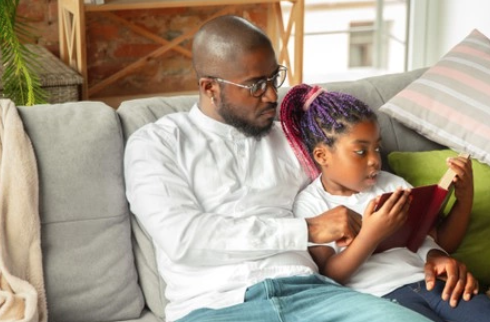 Father and daughter studying book together at home